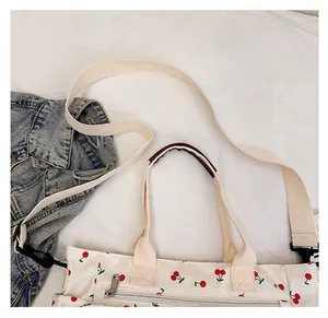 Détail d'un sac cabas en toile à motif cerises avec poignées renforcées et fermeture zippée