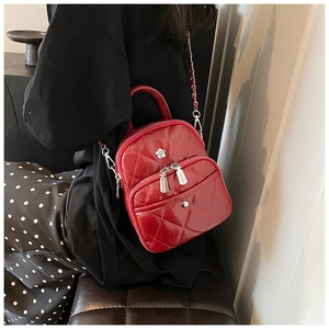 Detail view of red quilted crossbody bag with silver flower logo and chain strap
