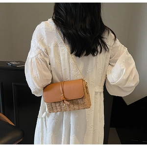 Straw flap crossbody bag with brown leather accent and gold chain strap on model