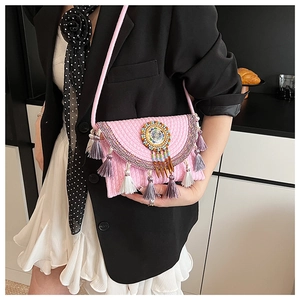 Close-up of pink bohemian knit crossbody bag with vibrant tassels and beaded ethnic charm