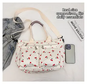Vue détaillée d'un cabas en toile blanc à motif cerises avec plusieurs poches zippées devant