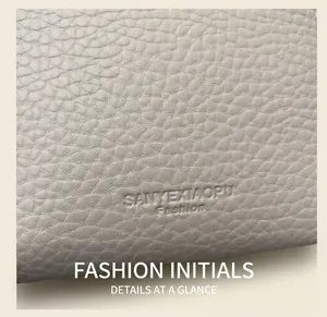 Close-up of pebble grain leather texture with embossed fashion logo on beige bucket bag