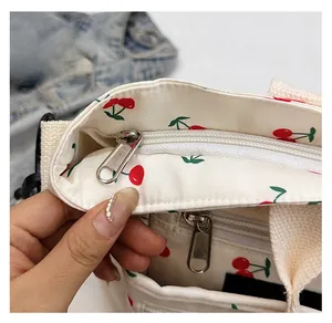 Gros plan sur la fermeture éclair fluide et l'imprimé cerises du sac cabas en toile