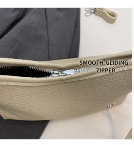 Detail shot of smooth silver metal zipper on beige lychee grain leather square bag