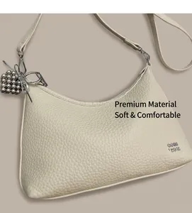 Close-up of cream pebble leather hobo bag with heart charm and silver metal logo