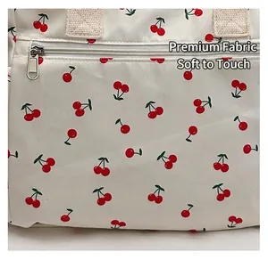 Gros plan du tissu blanc du cabas avec motif cerise et détails de fermeture éclair