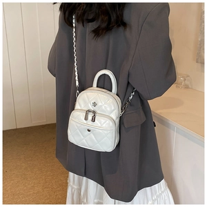 Detail showing white quilted mini backpack with silver chain strap on a blazer model