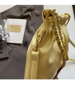 Detail of cream quilted leather texture with gold metal chain strap on a designer shoulder bag