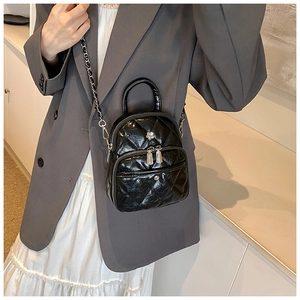 Detail of black quilted leather mini bag with silver flower logo and chain strap