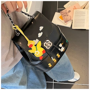 Detail eines schwarzen Kunstlederrucksacks mit Entenstickerei und Blumenschloss