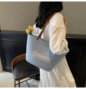 Détail du sac cabas tissé bleu clair avec broderie Summer et anses en cuir marron