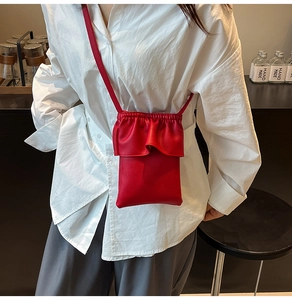 Détail du mini sac bandoulière rouge en cuir grainé avec bordure volantée sur chemise
