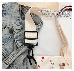 Détail de la bandoulière réglable avec boucle noire sur un sac en toile à cerises