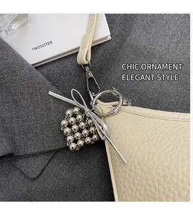 Close-up of lychee grain cream bag with heart bead charm and silver ribbon bow