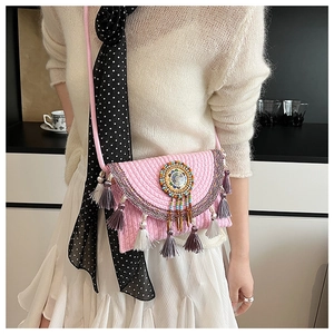 Detail of pink knitted crossbody bag with colorful ethnic beads and fringed tassels