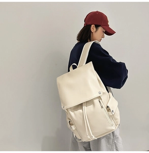 Side view of a large cream PU leather backpack with drawstring closure worn by a model