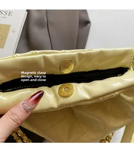 Detail of magnetic snap closure on a yellow quilted chain bag with rhomboid stitching