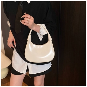 Dettaglio di modella con borsa a mezzaluna color crema in ecopelle lucida di alta qualità