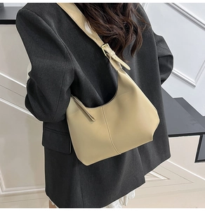 Detail of adjustable golden buckle and cream faux leather strap on minimalist shoulder bag