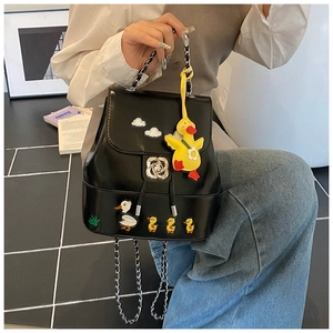 Detail eines schwarzen Lederrucksacks mit Entenstickerei, Blumenverschluss und Kettenriemen