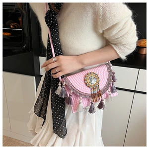 Detailed close-up of pink knitted boho bag with colorful beaded disk and stylish tassels