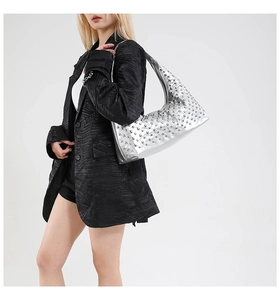 Detail of silver metallic hobo bag featuring dense studded rivets and moon shape