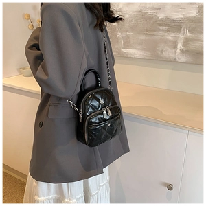 Quilted black patent leather mini crossbody bag with silver chains worn by model