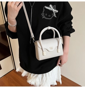 Vue détaillée du sac bandoulière blanc avec texture tissée et logo PAN TOR sur pull noir