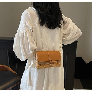 Detail of trendy straw crossbody bag with brown leather flap and gold chain strap