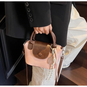Detail shot of a mini pink and brown crossbody bag with tennis racket charm and metal hook