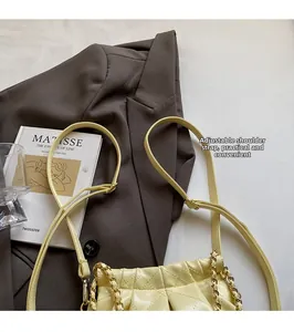 Detail of cream quilted shoulder bag featuring gold chain and adjustable strap