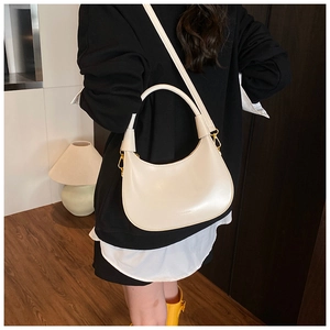 Borsa hobo a mezzaluna beige crema indossata a spalla da una modella per un look chic