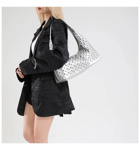 Close-up of a silver rivet hobo shoulder bag styled with a professional black blazer