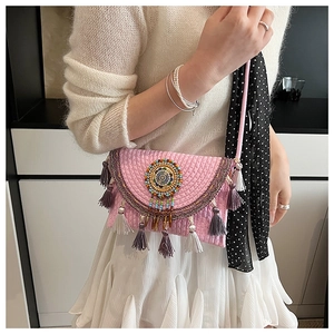 Detail of ethnic knit crossbody bag with colorful beadwork and vibrant tassel accents