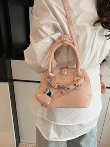 Sac à main rétro rose avec chaîne et breloque coeur porté sur une chemise blanche