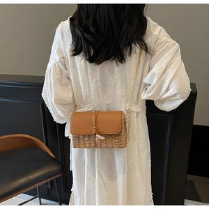 Detail of bohemian straw shoulder bag with leather flap and gold chain strap