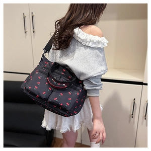 Détail d'un sac cabas en nylon à imprimé cerise avec double zip et poignées rouges