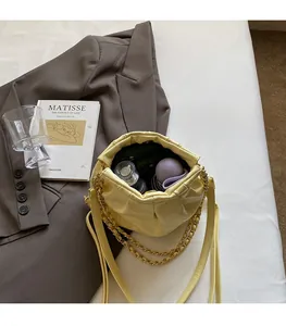 Detail view of cream quilted bucket bag showing spacious interior and gold chain strap