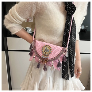 Detail of pink knitted crossbody bag with colorful bead patterns and fringe accents