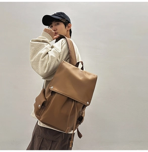 Detail view of a vintage brown leather travel backpack with side pocket and flap closure
