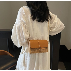 Detail of a straw crossbody bag with brown leather flap and golden ring buckle