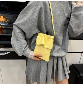 Détail d'un mini sac seau jaune en cuir avec rabat à volants et bandoulière amovible