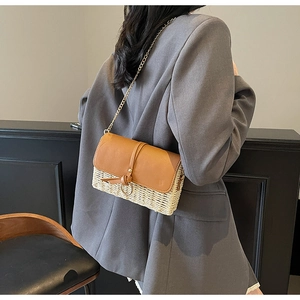 Detail of straw and brown leather crossbody bag with metal ring shown on grey blazer