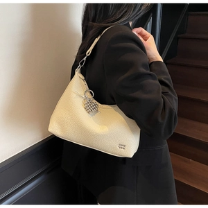 Close-up of cream pebble leather crescent bag with silver beaded charm detail