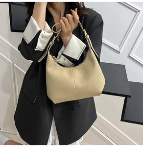 Detail of beige crescent underarm bag showing smooth leather texture and gold hardware