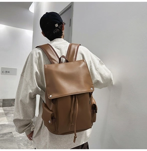 Brown leather backpack with double buckle and drawstring shown on a model