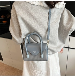 Détail du sac bandoulière bleu clair avec logo PAN TOR et poignée ronde porté par mannequin