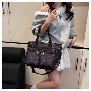 Détail du sac fourre-tout noir avec motifs de cerises rouges et poches zippées pratiques