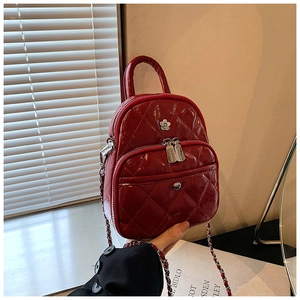 Détail d'un mini sac matelassé rouge avec bandoulière chaîne et boucle fleurie chic