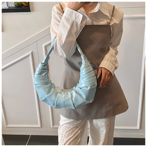 Close-up of light blue pleated croissant shoulder bag in glossy patent leather finish